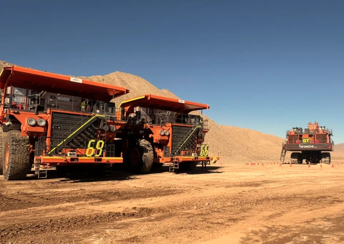 Haul trucks lined up on a mine floor under a clear sky